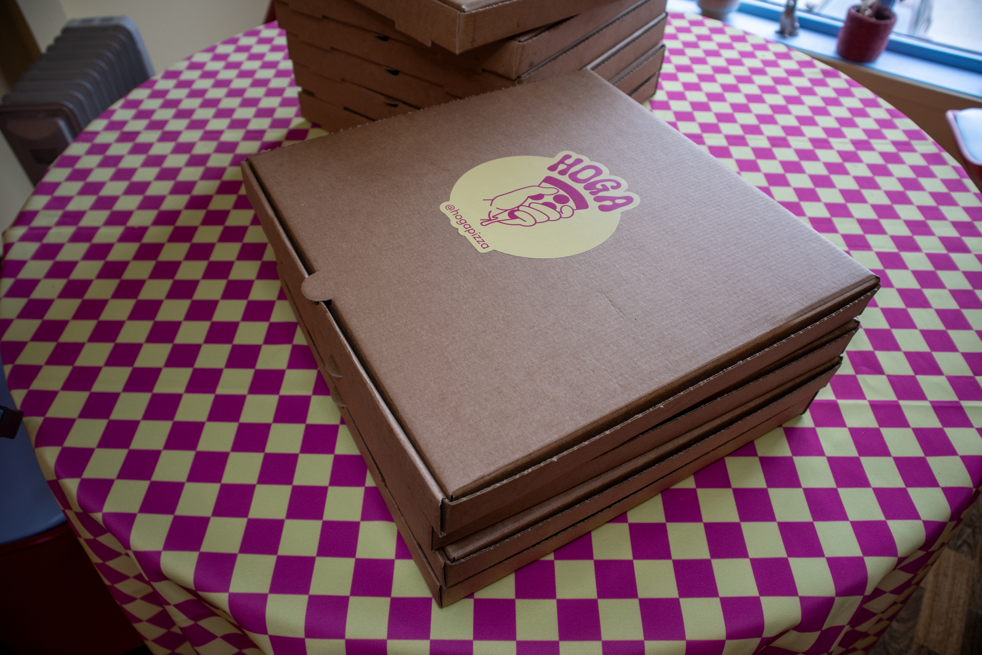 Stablede Hoga Pizza-esker på rutete duk, klare til levering og take-away frå Bryne Torg.